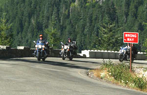four bikers passing a sign that says "wrong way"